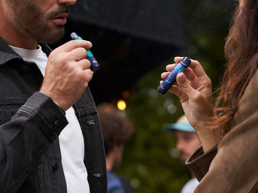 Žena a muž fajčia vape na verejnosti.