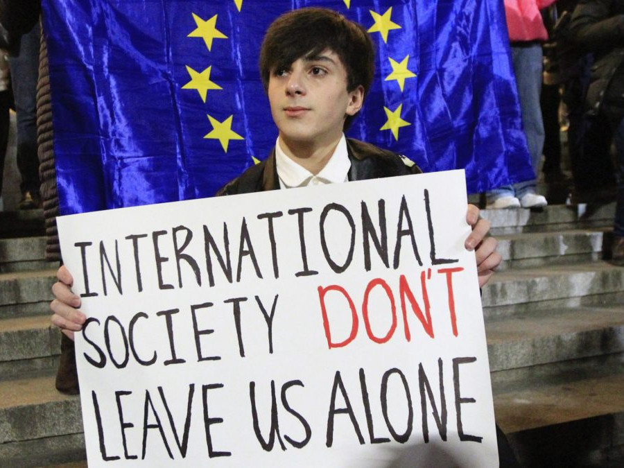 Muž drží plagát počas protestu opozície proti výsledkom volieb v gruzínskom Tbilisi.