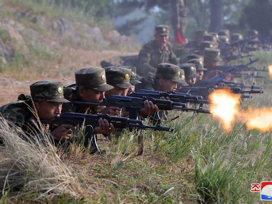 Na snímke severokórejskí vojaci ležia v tráve a strieľajú zo zbraní.