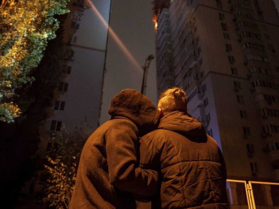 Pár sa navzájom utešuje pri sledovaní požiaru v obytnej budove.