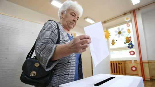 Volička vhadzuje obálku s hlasovacím lístkom do volebnej schránky.