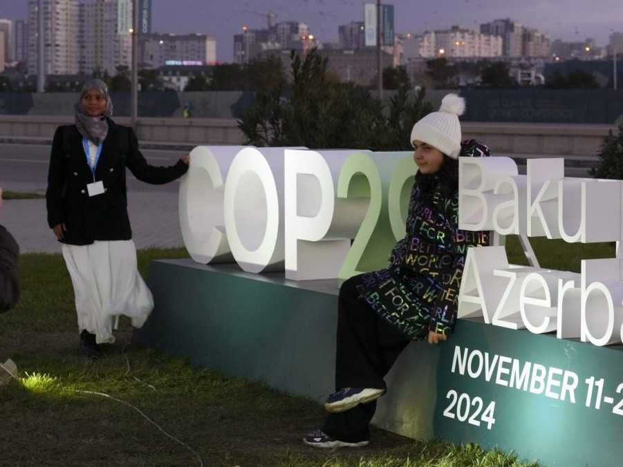 Ľudia pózujú pri logu v dejisku Klimatickej konferencie OSN COP 29 v Baku.