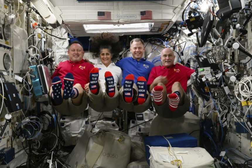 Zľava astronauti Butch Wilmore, Suni Williams, Nick Hague a Don Pettit ukazuj&uacute; ponožky s vlajkou USA na palube Medzin&aacute;rodnej vesm&iacute;rnej stanice v deň volieb.