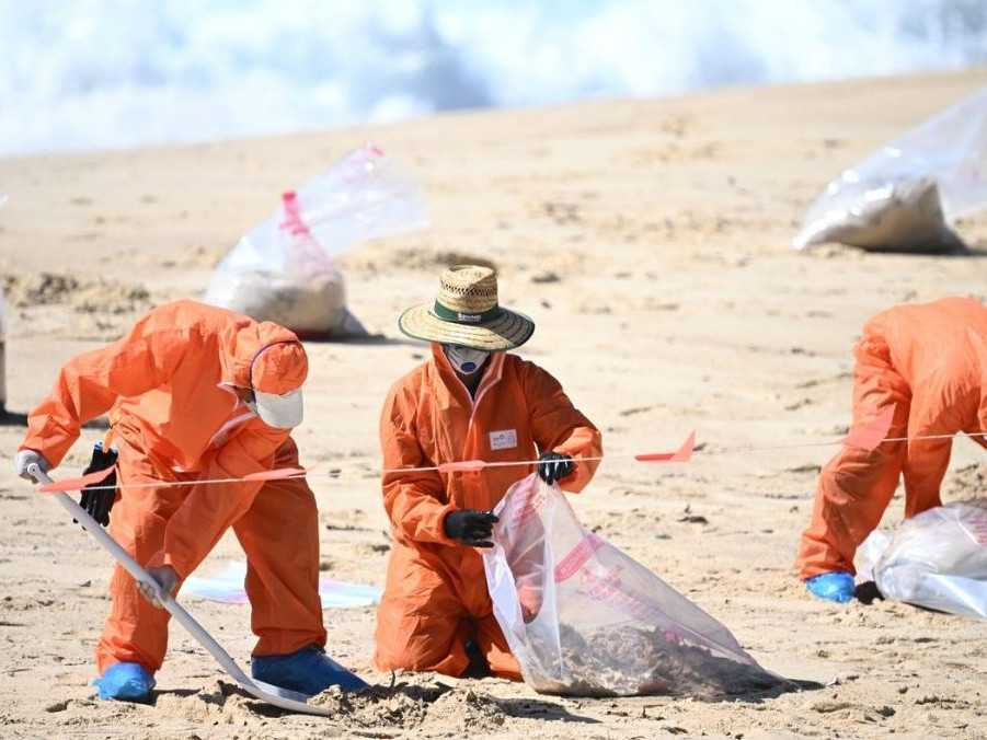 Na snímke pracovníci, ktorí čistia austrálsku pláž.