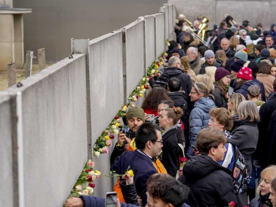 Na snímke ľudia kladúci kvety do štrbiny pozostatkov Berlínskeho múru.