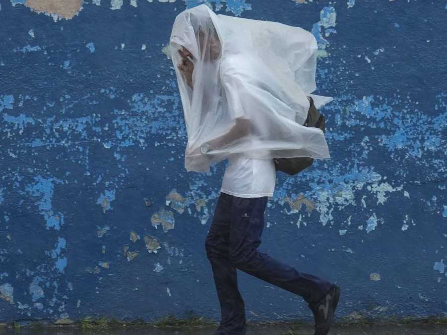 Na snímke muž počas hurikánu Rafael.