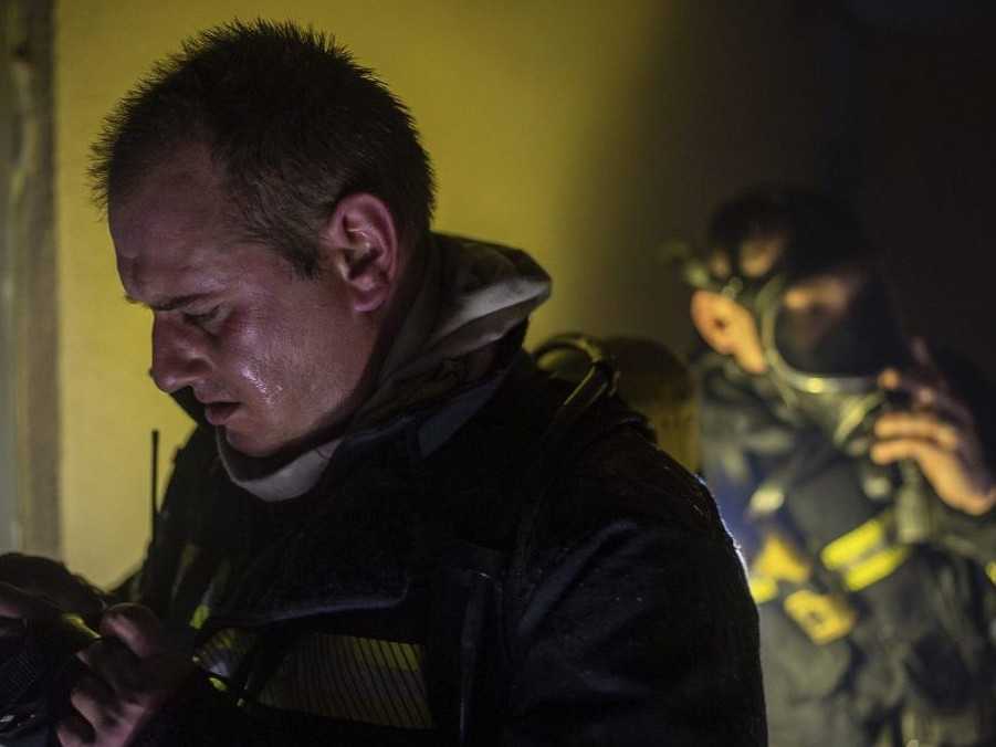 Hasiči majú na sebe kyslíkové masky pred vstupom na poschodie, ktoré zhorelo po ruskom útoku.