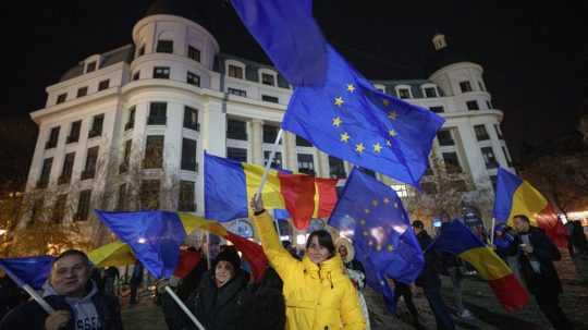 Ľudia mávajú vlajkami Rumunska a Európskej únie počas proeurópskeho zhromaždenia.