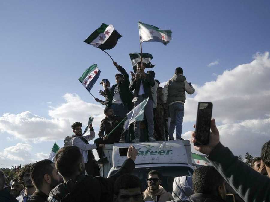 Sýrčania mávajú sýrskymi opozičnými zástavami na centrálnom námestí v Damasku.