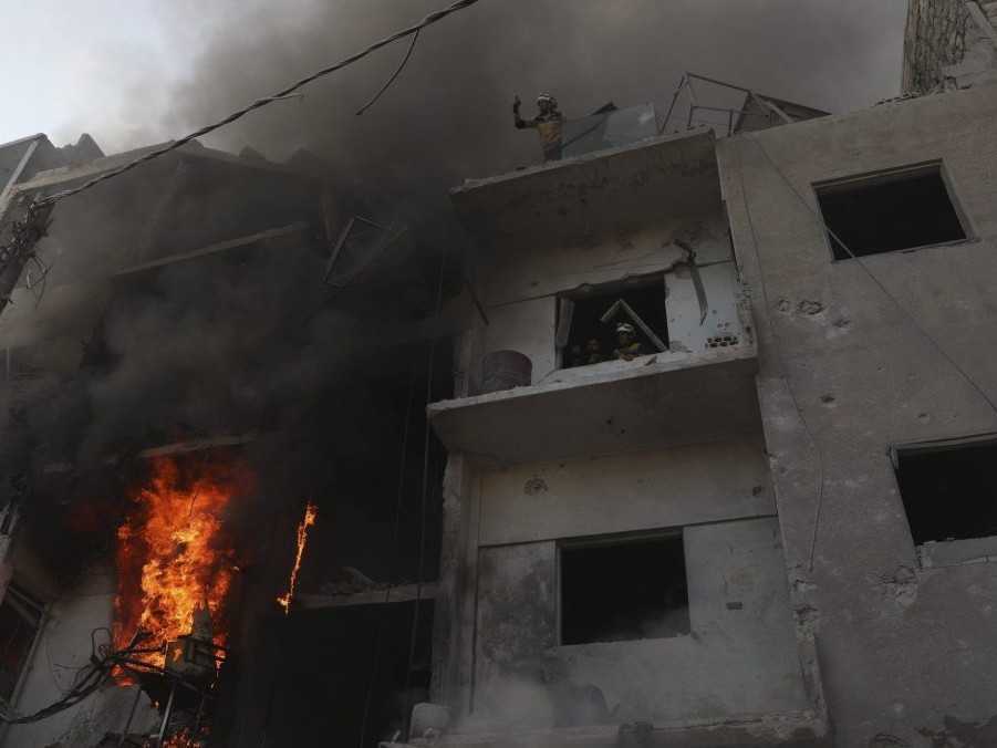 Záchranári v horiacej budove po útoku sýrskych vládnych síl v sýrskom meste Idlib.