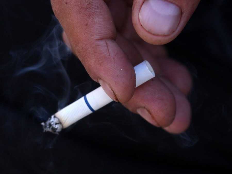 Na snímke osoba drží zapálenú cigaretu.