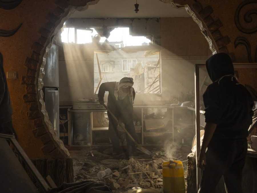 Palestínčania sa pozerajú na poškodený dom svojho suseda po izraelskom útoku v Rafahu.