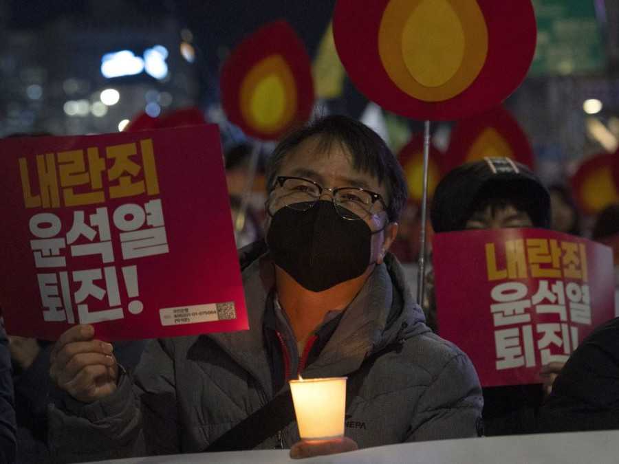 Protestujúci muž drží trasnparent s nápisom "Jun Sok-jol, odstúp".