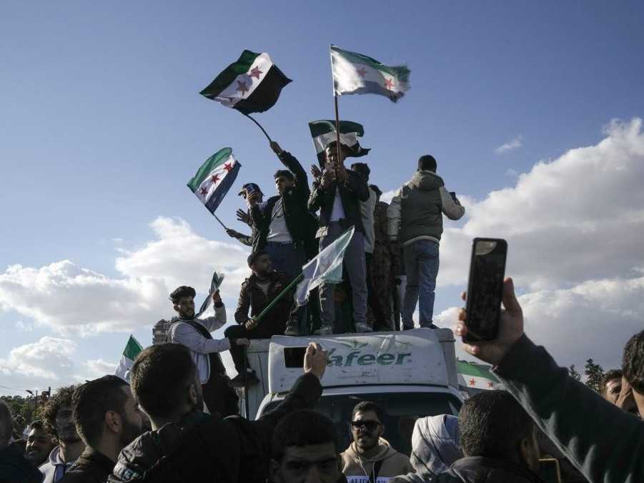 Na ilustračnej snímke Sýrčania mávajú opozičnými vlajkami.