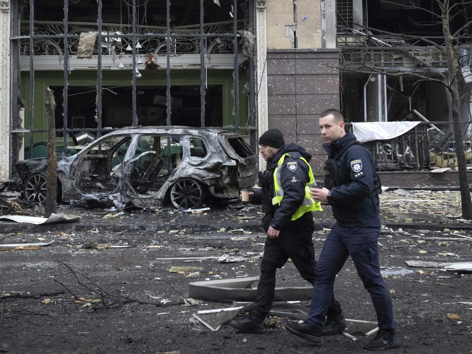 Policajti kráčajú popri zničených budovách. (Ilustračná fotografia)