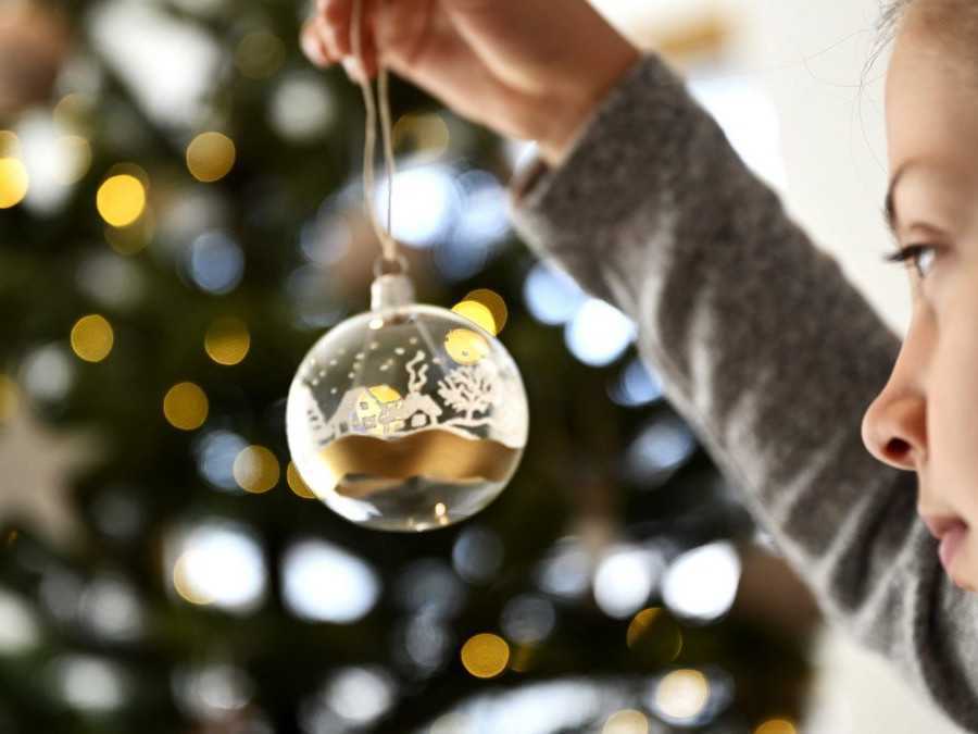 Na snímke dievča zdobí vianočný stromček.