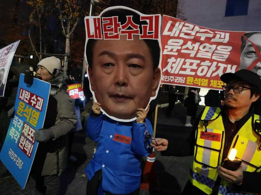 Účastník s maskou juhokórejského prezidenta na zhromaždení.