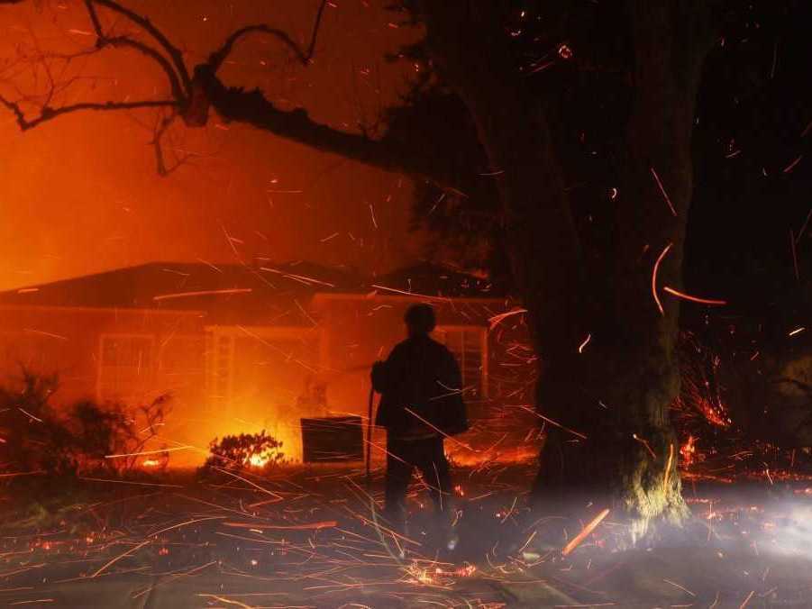 Osoba sa snaží hadicou uhasiť žeravé uhlíky z požiaru.