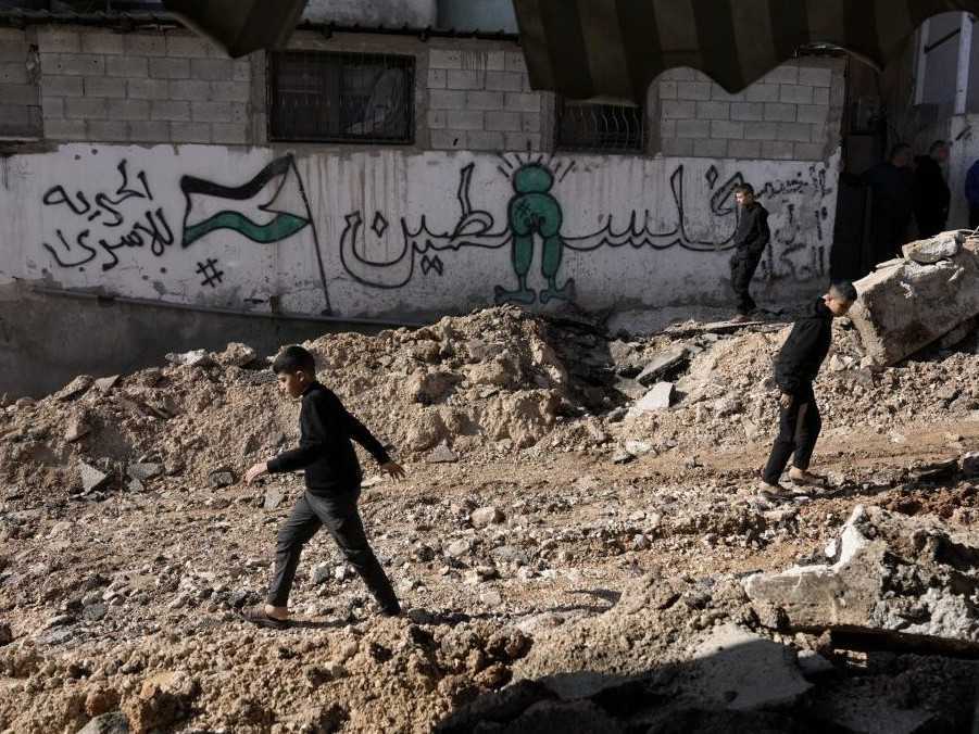 Na ilustračnej snímke palestínske deti pobehujúce v ruinách.