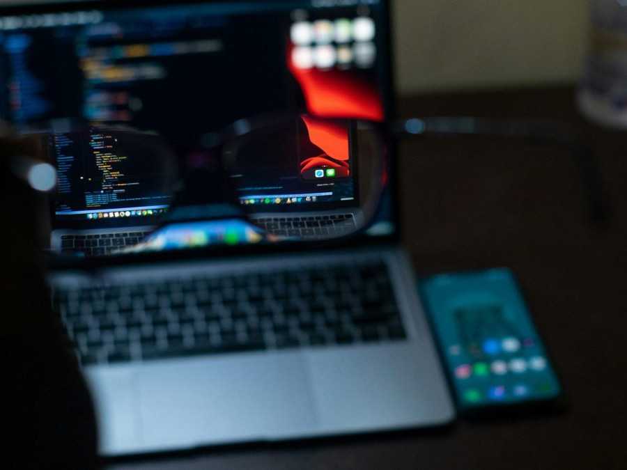 Na snímke je osoba s okuliarmi pred notebookom - na notebooku je kód.