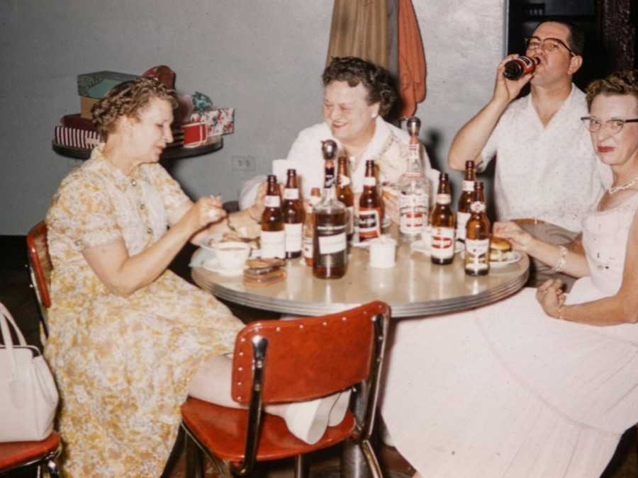 Na snímke osoby pri stole pijú alkohol.