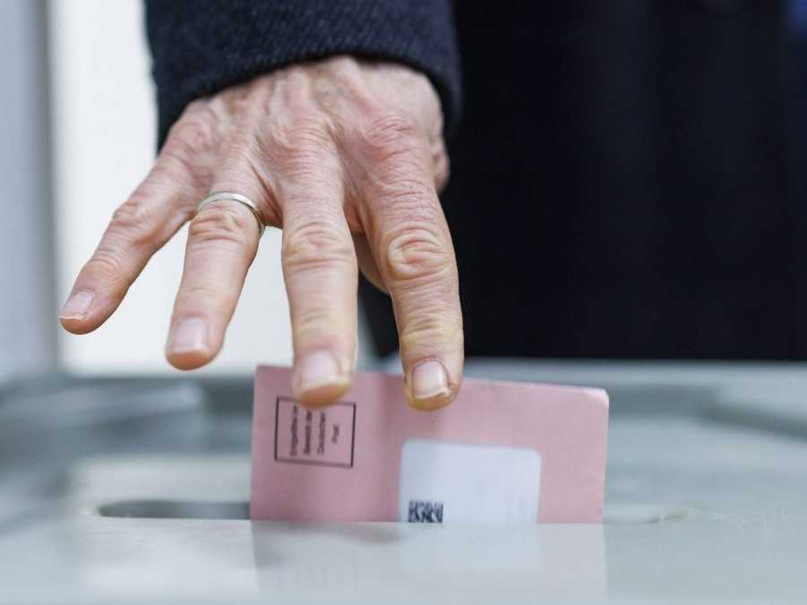 Muž vhadzuje hlasovací lístok do volebnej schránky v Nemecku.