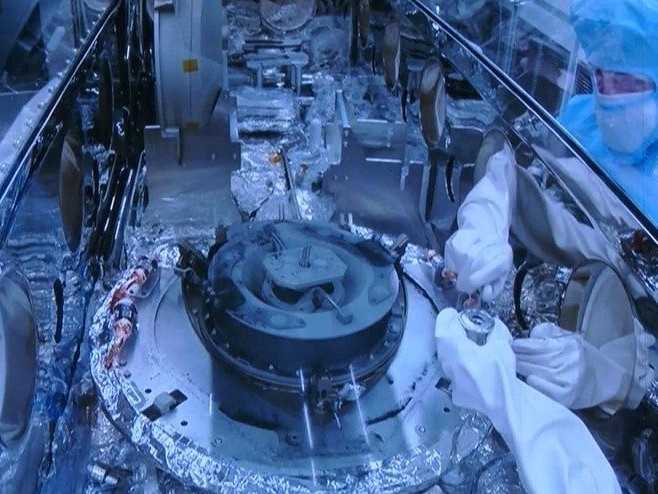 Na snímke vedci pri skúmaní vzoriek z asteroidu.