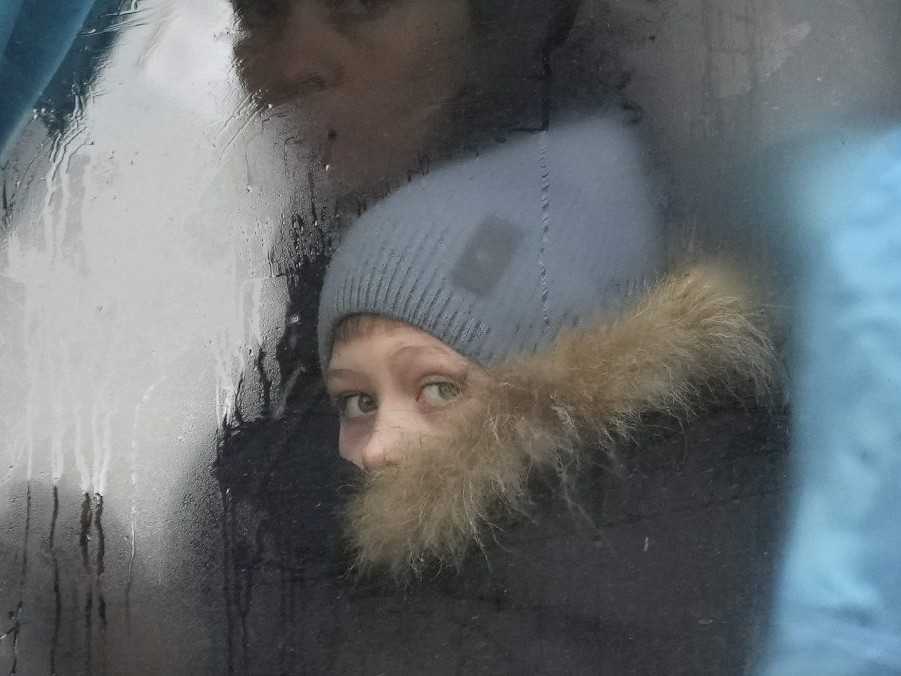 Žena a dieťa z Ukrajiny sa pozerajú z okna autobusu.