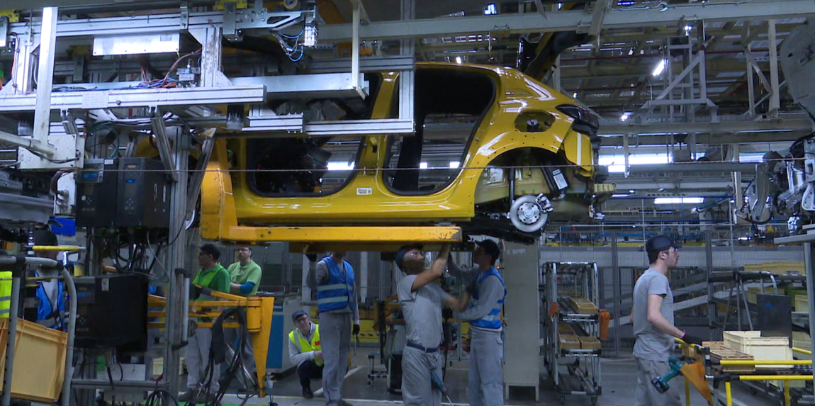 Na snímke sú zamestnanci pri výrobe automobilu.