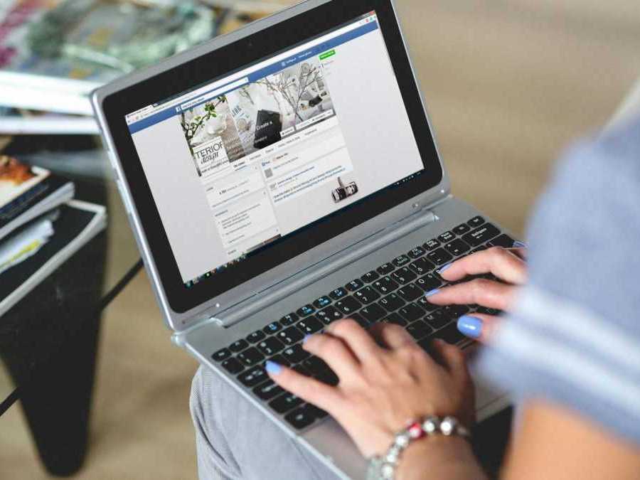 Žena na snímke pracuje na notebooku, používa sieť facebook.