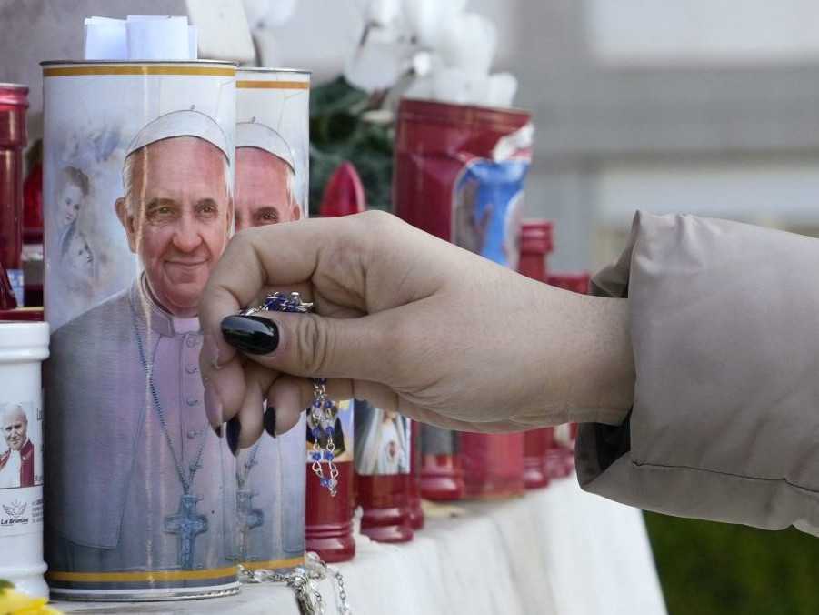 Žena kladie ruženec k sviečkam