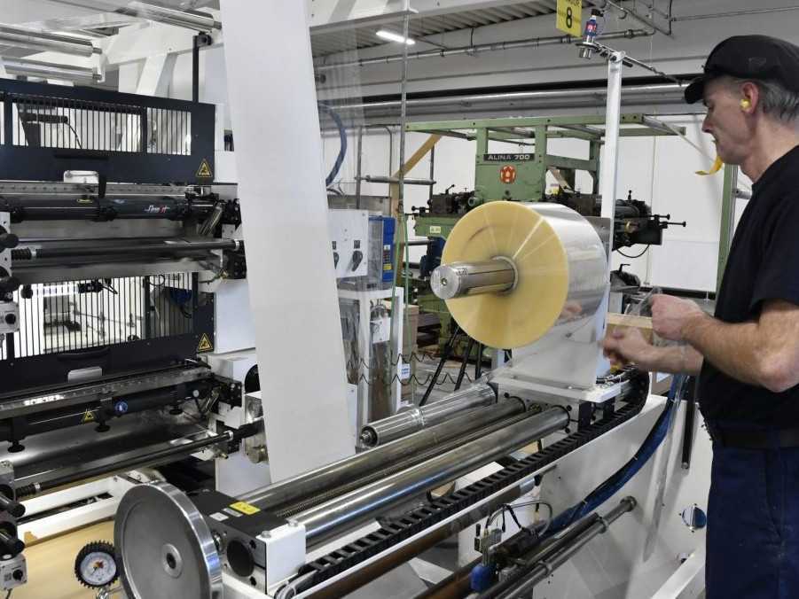 Zamestnanec v závode pri papierenskom stroji.