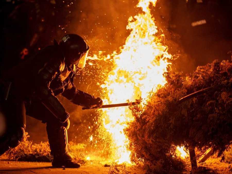 Policajt sa pokúša uhasiť požiar, ktorý zapálili priaznivci rumunského krajne pravicového politika Calina Georgesca.
