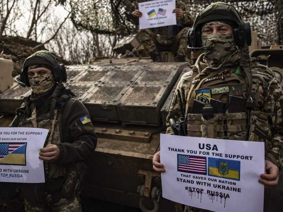 Vojaci 100. ukrajinskej mechanizovanej brigády držia plagáty s poďakovaním USA za podporu.