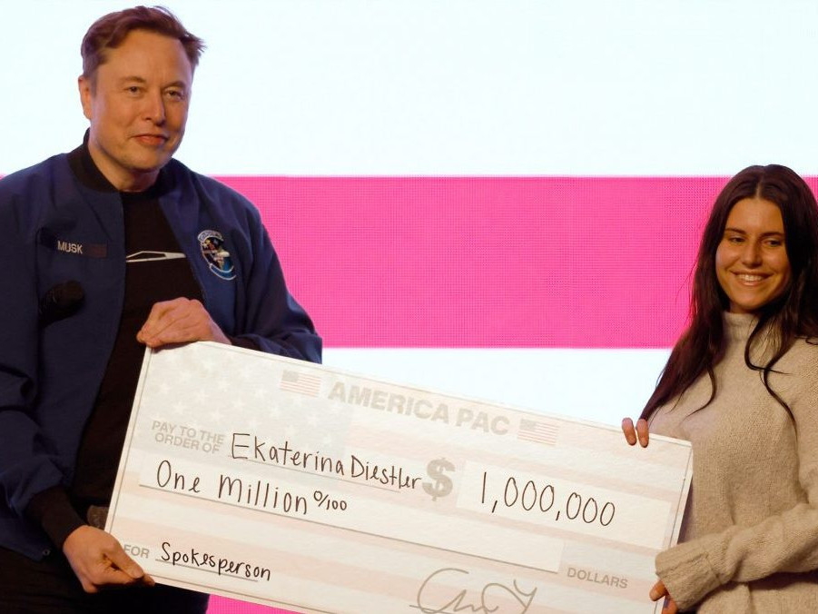 Elon Musk odovzdáva šek na milión dolárov.