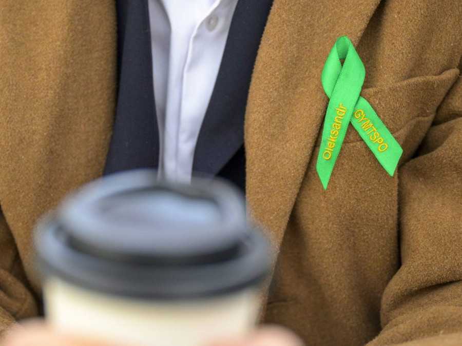 Maturant v ruke drží kávu a na kabáte má pripnutú maturantskú stušku.