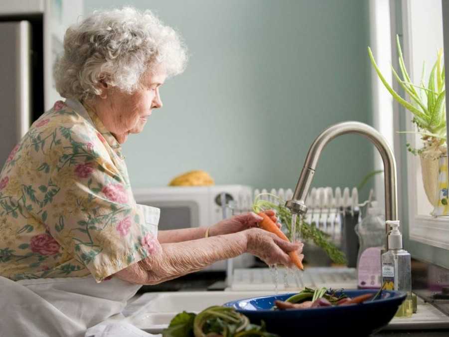 Seniorka umýva zeleninu.