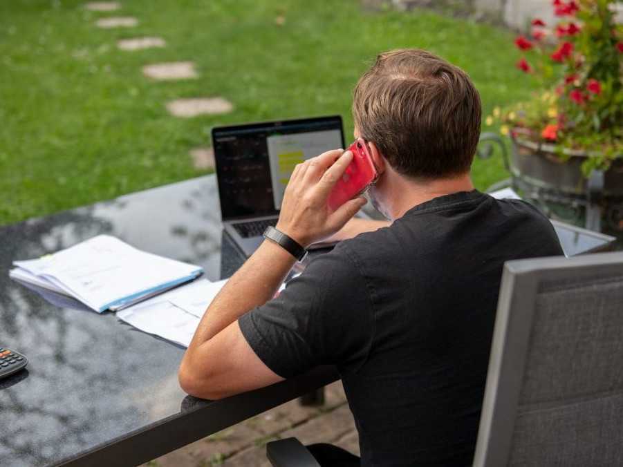 Muž sedí doma v záhrade a pracuje na svojom notebooku.