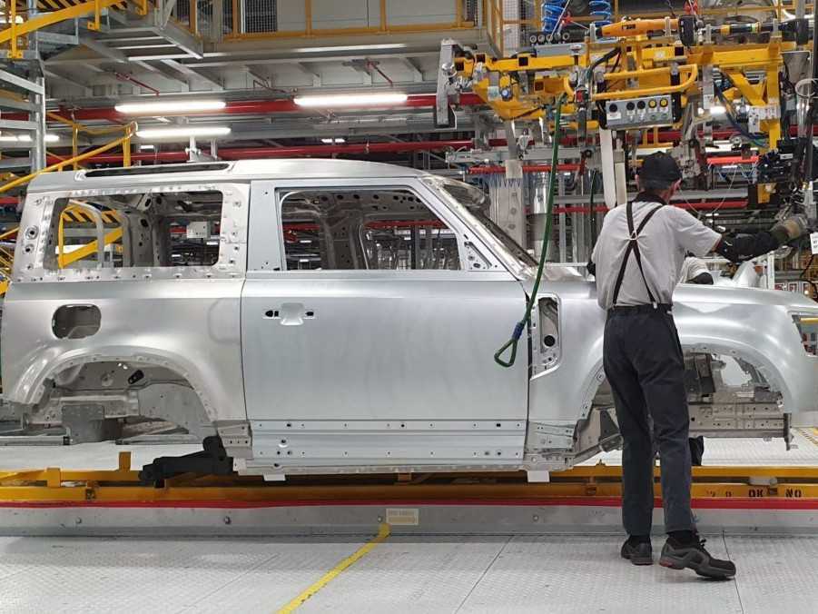 Zamestnanec obsluhuje montážnu linku modelu automobilu Land Rover Defender.