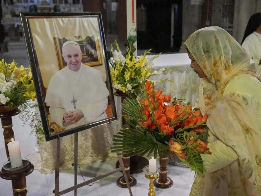 Kresťanka pokladá kvety pred portrét pápeža Františka počas obradu na jeho počesť.