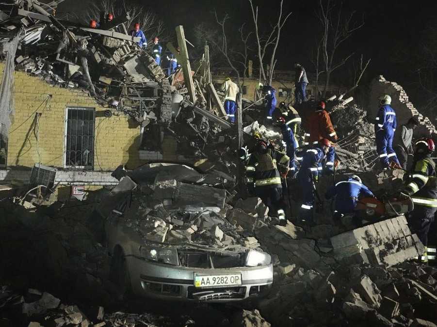 Ukrajinskí záchranári prehľadávajú trosky obytnej budovy, ktorú zasiahol ruský útok na Kyjev.