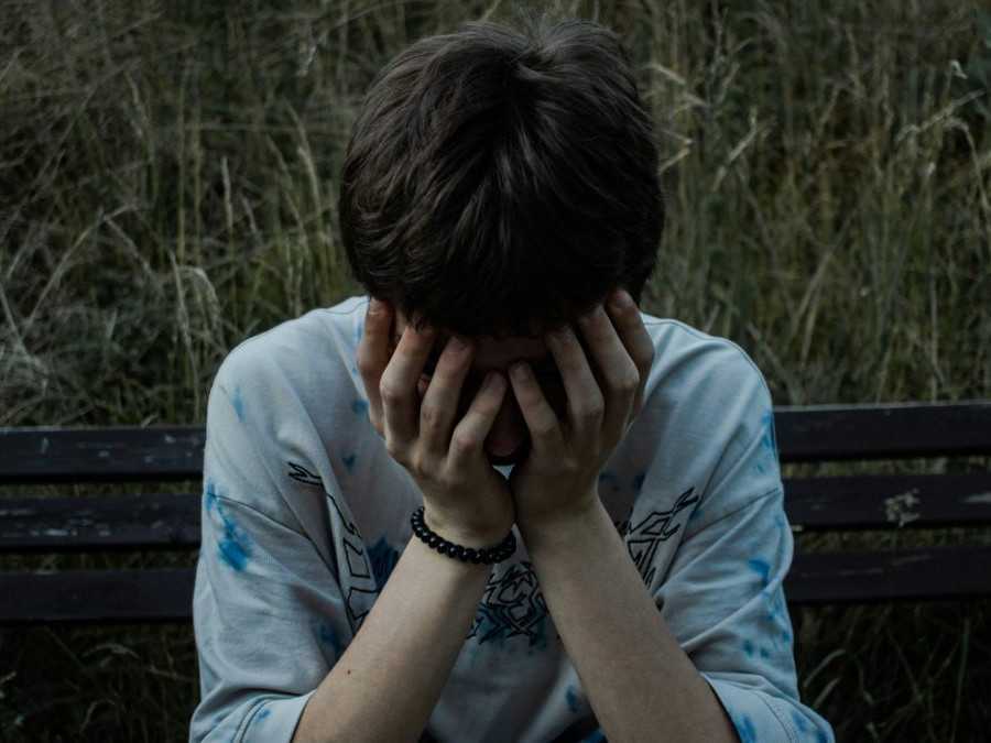 Dieťa sedí na lavičke, zakrýva si stvár.