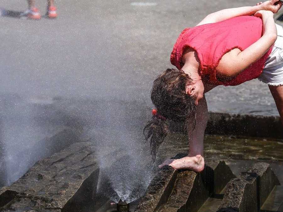 Na ilustračnej snímke si žena ovlažuje hlavu vo fontáne.