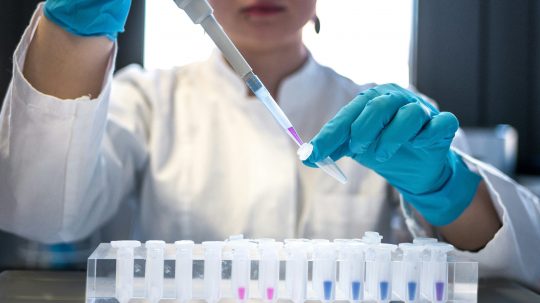 Vedkyňa v laboratóriu prelieva pipetou tekutiny do skúmaviek.