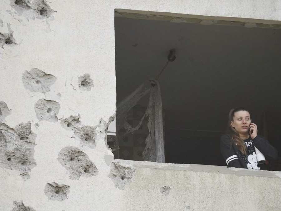 Na ilustračnej snímke sa žena pozerá cez okno zničeného bytu v Charkove.