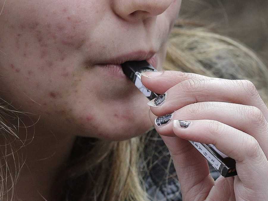 Na ilustračnej snímke si žena poťahuje z e-cigarety.