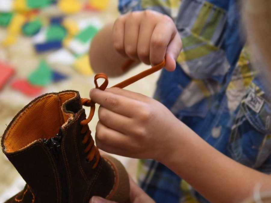 Na ilustračnej snímke chlapec ukazuje, ako si zaviazať šnúrky počas zápisu.