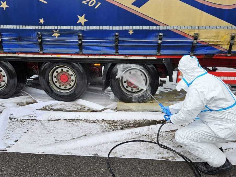 Pracovník dezinfikuje nákladné vozidlá prechádzajúce cez hranice.
