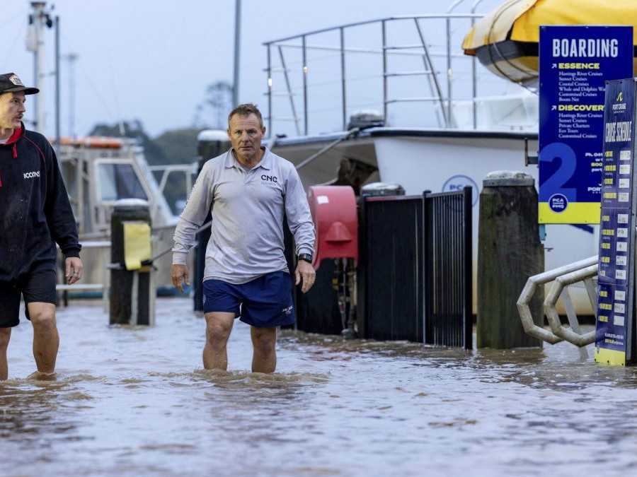 Muži kráčajú zaplavenými ulicami Syndey v Austrálii.
