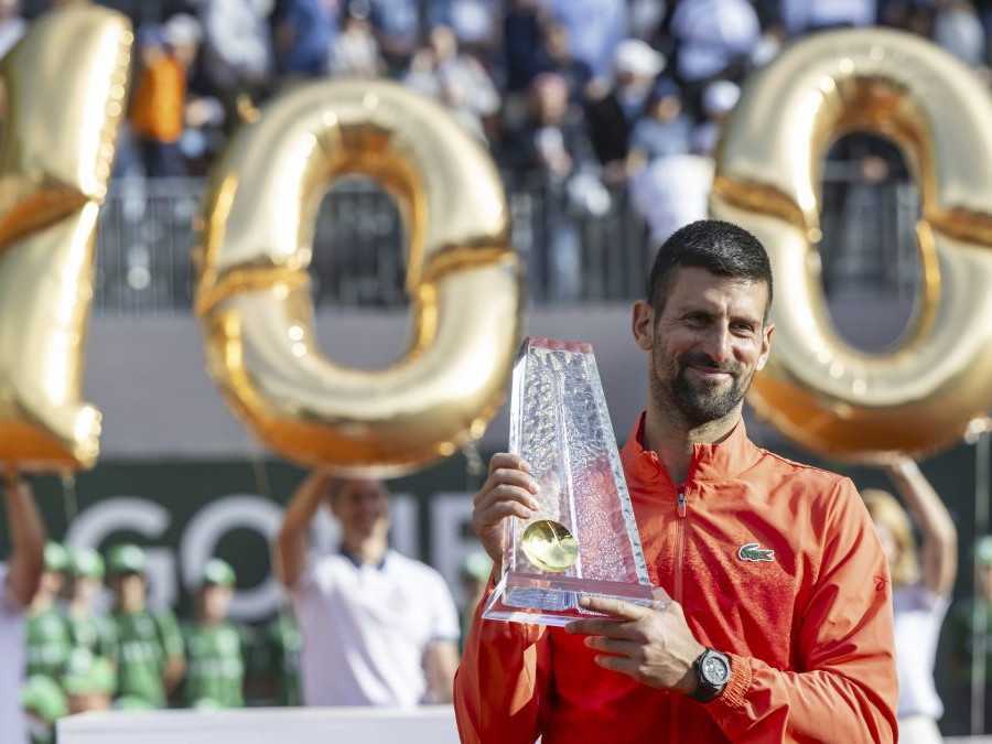Novak Djokovič, za ním balóny v tvare čísla 100.